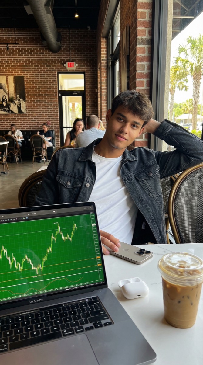 Luiz no café com MacBook e iPhone acompanhando o mercado